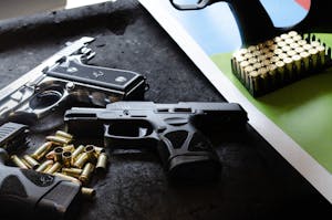 Close-up of guns and ammunition on a table, highlighting safety and weaponry themes.