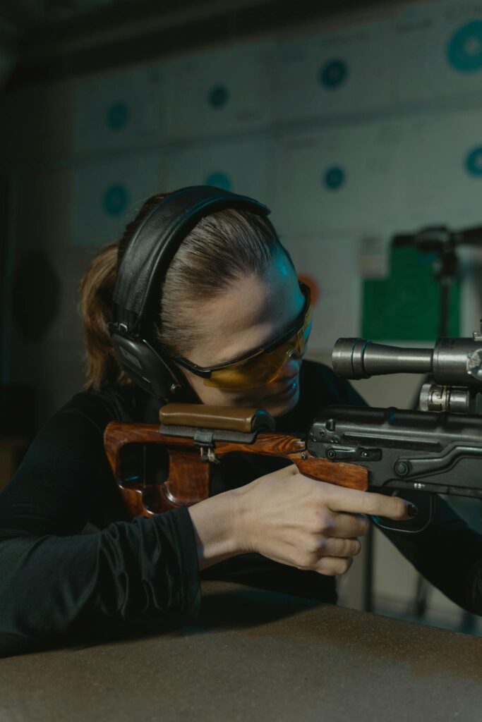 Focused woman aiming a rifle during an indoor shooting practice session.