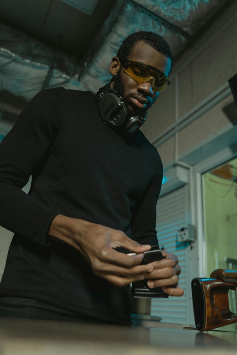 Man wearing protective gear assembling a gun magazine indoors.